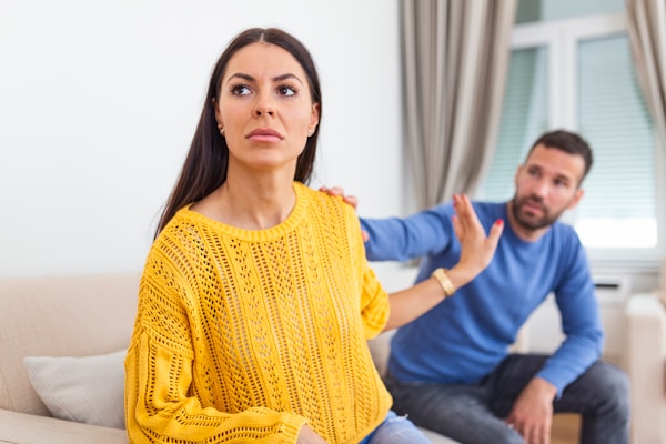 Woman looking distressed with man's hand on shoulder